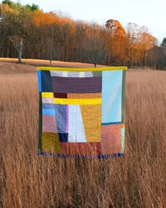 a patchwork quilt hanging in the middle of a field