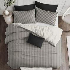 black and white striped bedding in a room with wood flooring, pillows and rugs