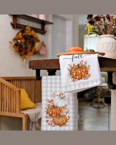 two towels hanging from a table with pumpkins on it and fall decorations in the background