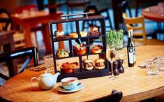 a wooden table topped with cups and saucers filled with different types of food on top of it