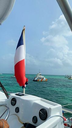 there is a flag that is on the back of a boat in the water with other boats