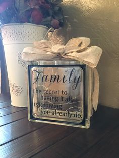 a glass block with the words family on it sitting next to a potted plant