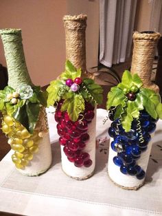 three wine bottles are decorated with grapes and leaves