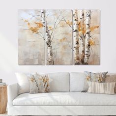 three paintings on the wall in a living room with white couches and coffee table