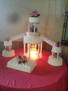 three tiered wedding cake sitting on top of a pink table cloth covered tablecloth