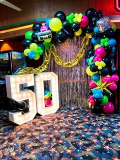 a 50th birthday decoration with balloons and streamers in the shape of a number 50