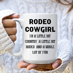 a woman is holding a coffee mug in her hands with the words rodeo cowgirl on it