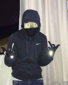 a man in a black hoodie with money on his face and two glowing hands