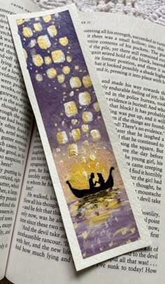 an open bookmark with two people in a boat floating on the water at night