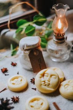 some cookies are sitting on a table next to a candle and glass vase with leaves