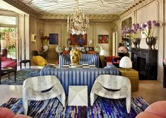 a living room filled with furniture and a chandelier hanging from the ceiling above it