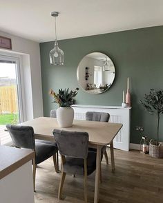 a dining room table with chairs and a mirror on the wall