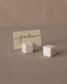 two small cubes sitting on top of a table next to a piece of paper