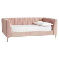 a pink velvet sofa with white pillows on the armrests and an open end