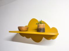 a yellow shelf with two vases on it and a plant sitting on top of the shelf