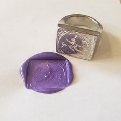 a wax stamp sitting on top of a table next to a metal container with a purple seal