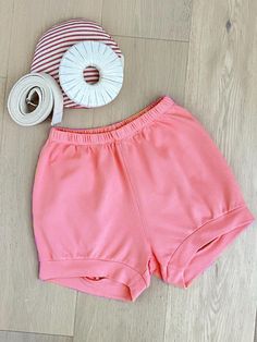 a pair of pink shorts and a spool of thread on the floor