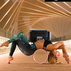 a woman is doing an acrobatic trick with a hula hoop on the floor