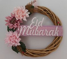 a close up of a wreath on a wall with flowers and the word eid mubarak