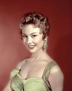 an old photo of a woman in a green dress with big earrings on her head