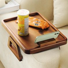 a wooden tray with a cell phone and paint on it sitting next to a couch