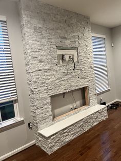 an empty living room with wood floors and white brick fireplace in the middle of it