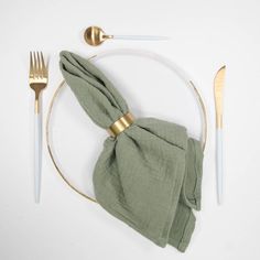 a place setting with napkin, fork and knife on a white tablecloth in the shape of a circle