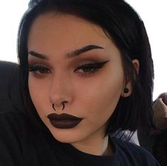 a woman with black lipstick and nose piercings