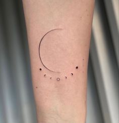 a small crescent tattoo on the right inner arm, with five dots in it and one dot at the bottom