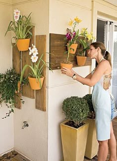 a woman placing potted plants on the wall