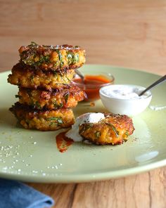 three crab cakes are stacked on top of each other with sour cream and sauce in the background