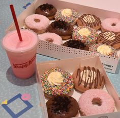 two boxes of doughnuts with frosting and sprinkles next to a drink