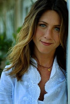 a woman leaning against a wall wearing a white shirt