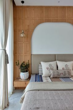 a large bed sitting next to a window with white curtains and pillows on top of it