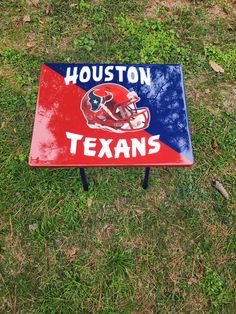 a red and blue sign that says houston texans on it in the middle of some grass