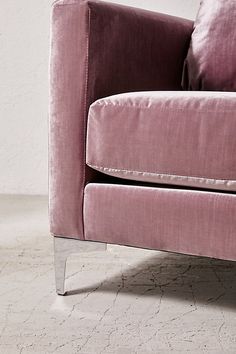 a pink velvet couch sitting on top of a white floor