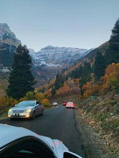 cars driving down the road in front of mountains