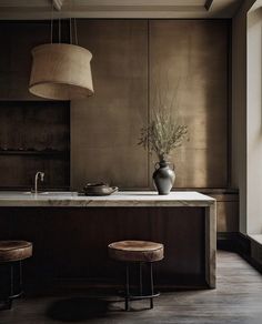 a kitchen island with two stools and a vase on it in front of a window