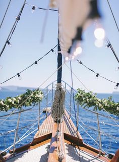 the bow of a sailboat with flowers on it's mast and lights hanging from the rig