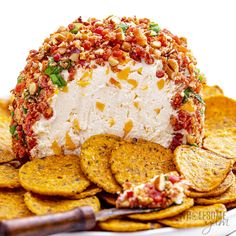 a cheese ball covered in toppings and surrounded by crackers