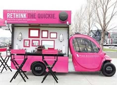 a pink car is parked in front of a booth with tables and chairs on it