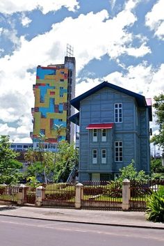 a large blue house sitting on the side of a road next to a tall building