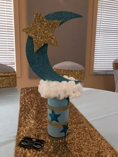 a blue cup with stars and clouds in it sitting on top of a gold table cloth