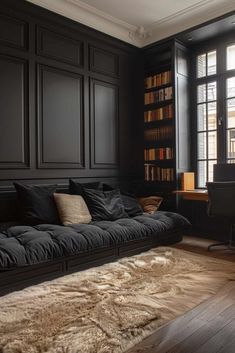 a living room filled with black furniture and lots of bookshelves on the wall