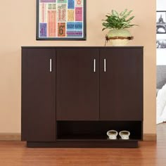 a brown cabinet sitting on top of a wooden floor next to a potted plant