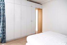 a white bed sitting in a bedroom next to a tall cabinet with doors on it