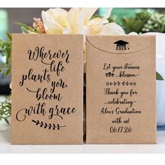 two brown paper bags with black lettering on them and flowers in the background, one has a white flower