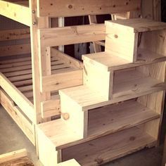 a bunk bed made out of wooden pallets in a storage area with stairs leading up to the top