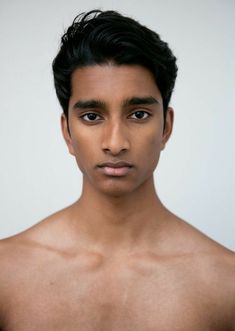 a young man with no shirt on posing for a photo in front of a white wall