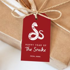 a gift wrapped in brown paper with a red tag that says happy year of the snake